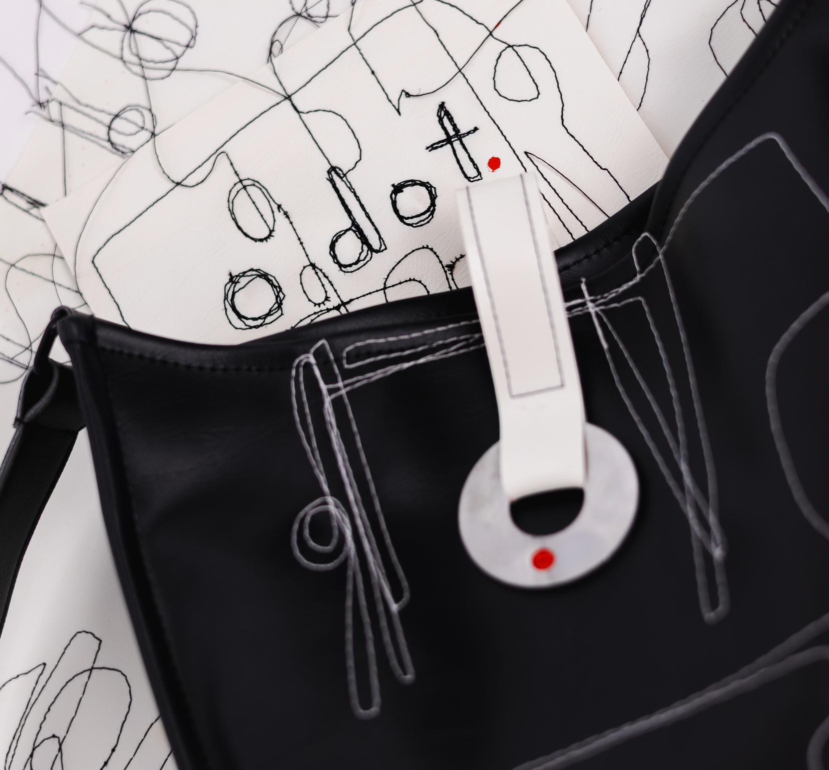 Black bag with white tag and abstract designs on a white background