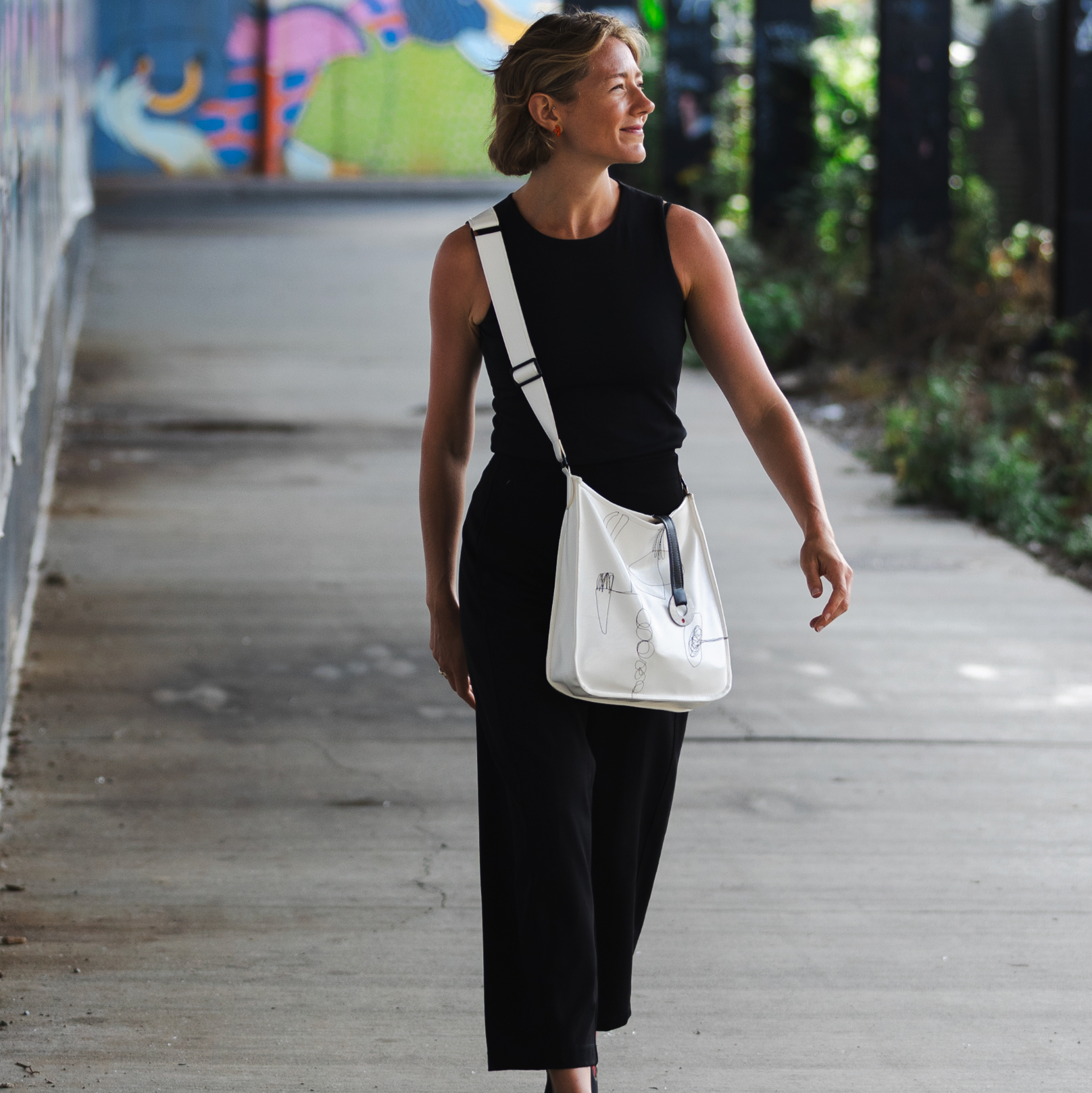 Woman walking outdoors with a white crossbody bag